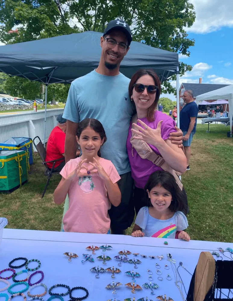 The family together behind a stall at an outdoor farmers market