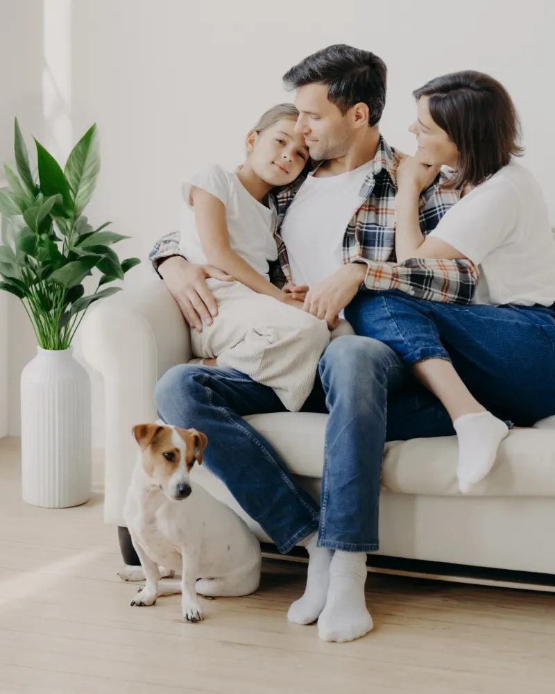 A family relaxing together with their dog in a clean, bright living room