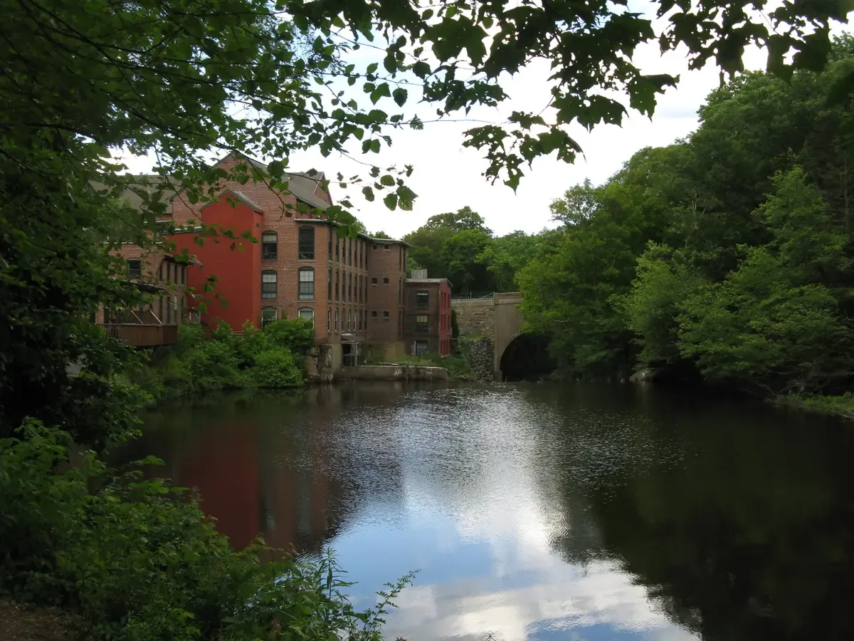 The brick Sanford Mills building reflected in the Charles River at Medway