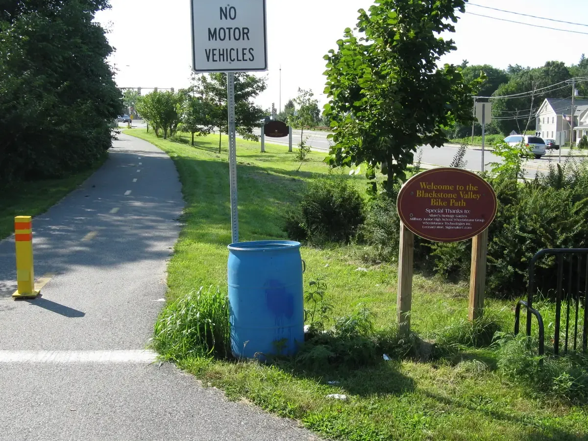 The paved Blackstone Valley Bike Path running past grass and trees in Millbury