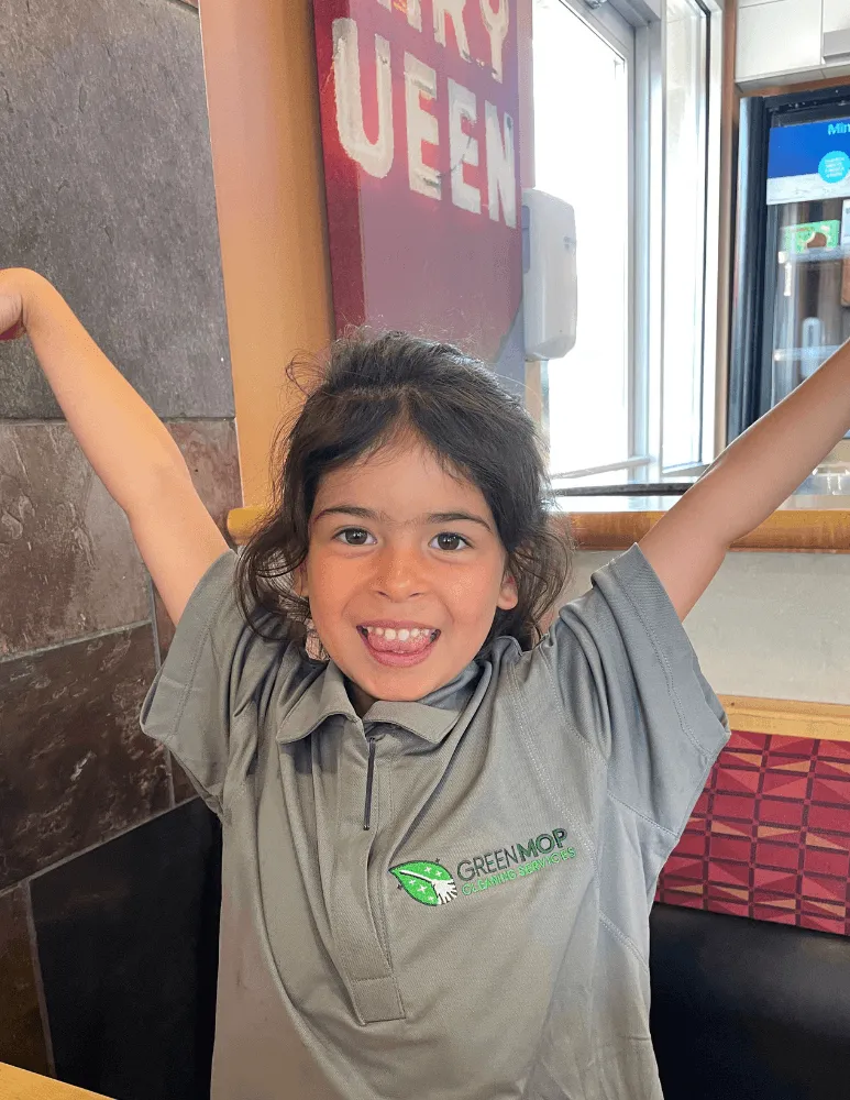 S. with her arms in the air, wearing a Green Mop polo shirt at Dairy Queen