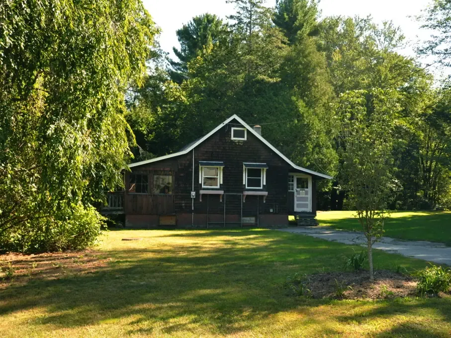 A wooden Civilian Conservation Corps building among trees in Upton State Forest